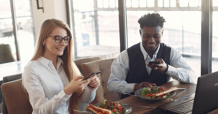 Dos millennials tomando fotos a su comida en restaurante