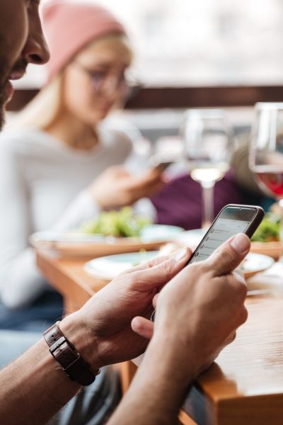 Manos sosteniendo celular en restaurante