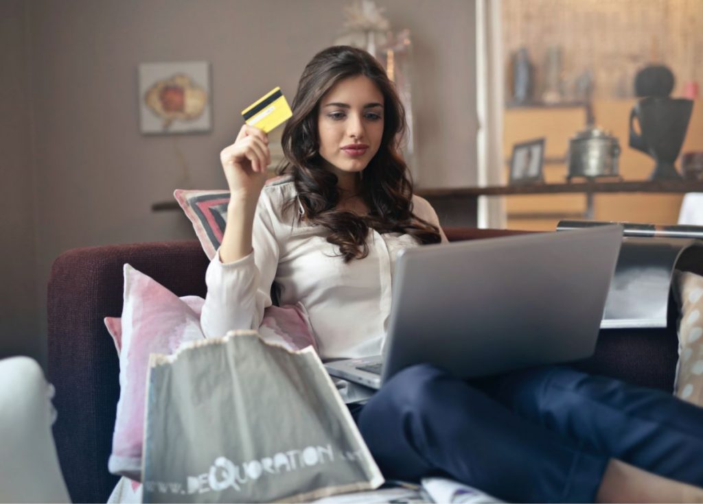 Chica sosteniendo tarjeta para realizar compra en tienda e-commerce
