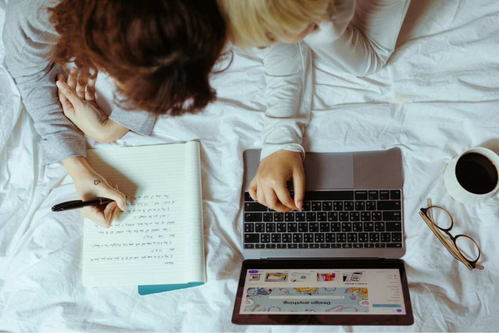 Aprendiendo posicionamiento SEO Chicas estudiando el posicionamiento SEO sobre la cama, con una laptop y cuadeno
