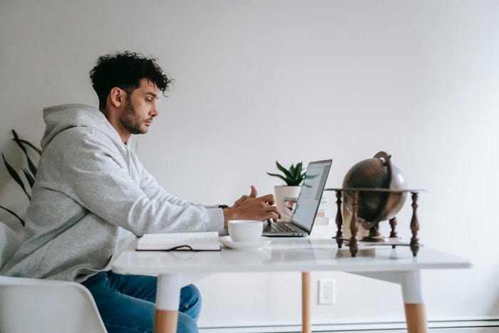 Hombre sentado con macbook creando plan de marketing Los 4 pasos de oro que te ayudarán a elaborar un plan de marketing digital, paso nro 3