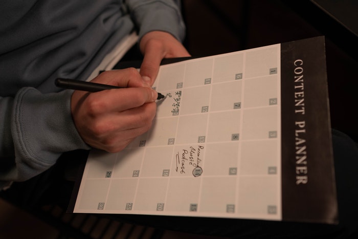 Chico tomando nota en calendario Podcast: Qué es y cómo puedes crear uno para tu marca, Paso 1: Planifica el contenido de tu podcast