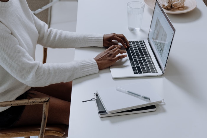 Chico escribiendo en macbook Podcast: Qué es y cómo puedes crear uno para tu marca, Paso 5: Promociona tu podcast