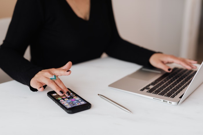 Mujer utilizando macbook y iphone Errores más comunes que puedes cometer al segmentar un mercado objetivo, No utilizar los canales de comunicación adecuados
